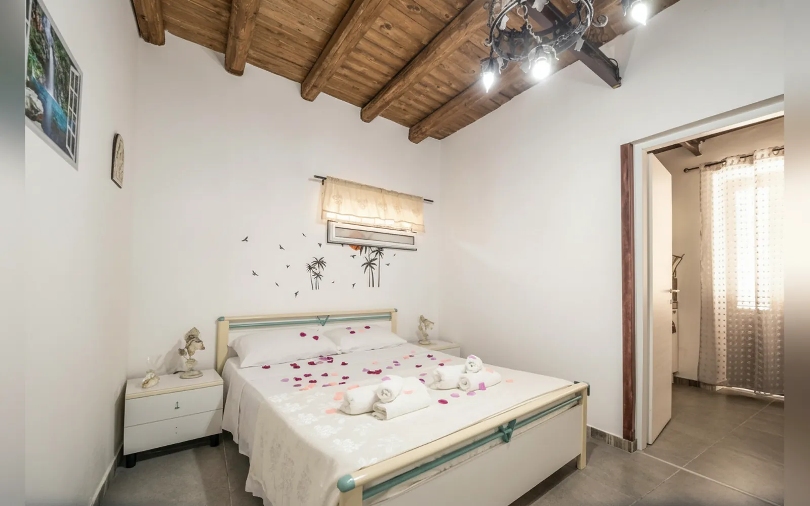 La camera con il letto matrimoniale, il soffitto con le travi in legno e il lampadario in ferro battuto