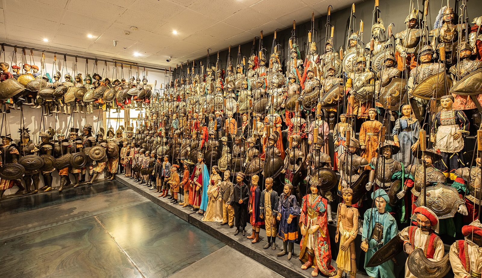 Una lunga parete di pupi siciliani in armatura, paladini e personaggi in costume esposti al Museo internazionale delle marionette di Palermo