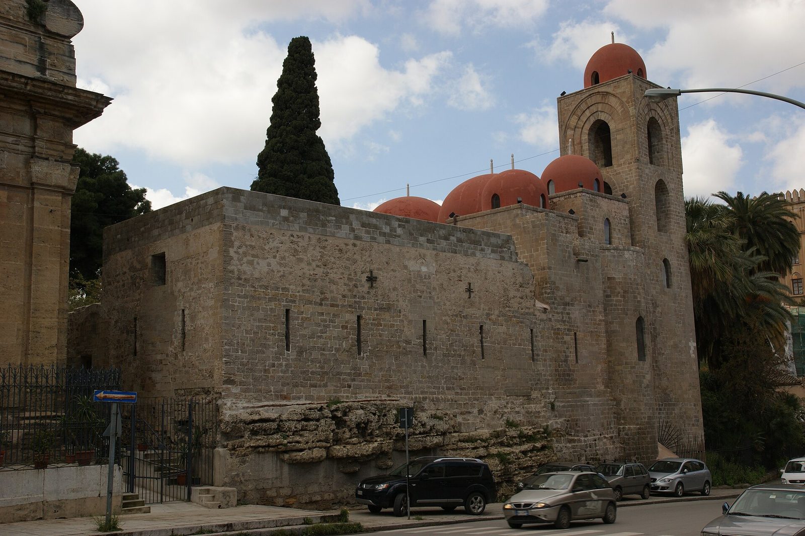 La chiesa di San Giovanni degli Eremiti a Palermo con le cupole rosse, il campanile in pietra e un alto cipresso
