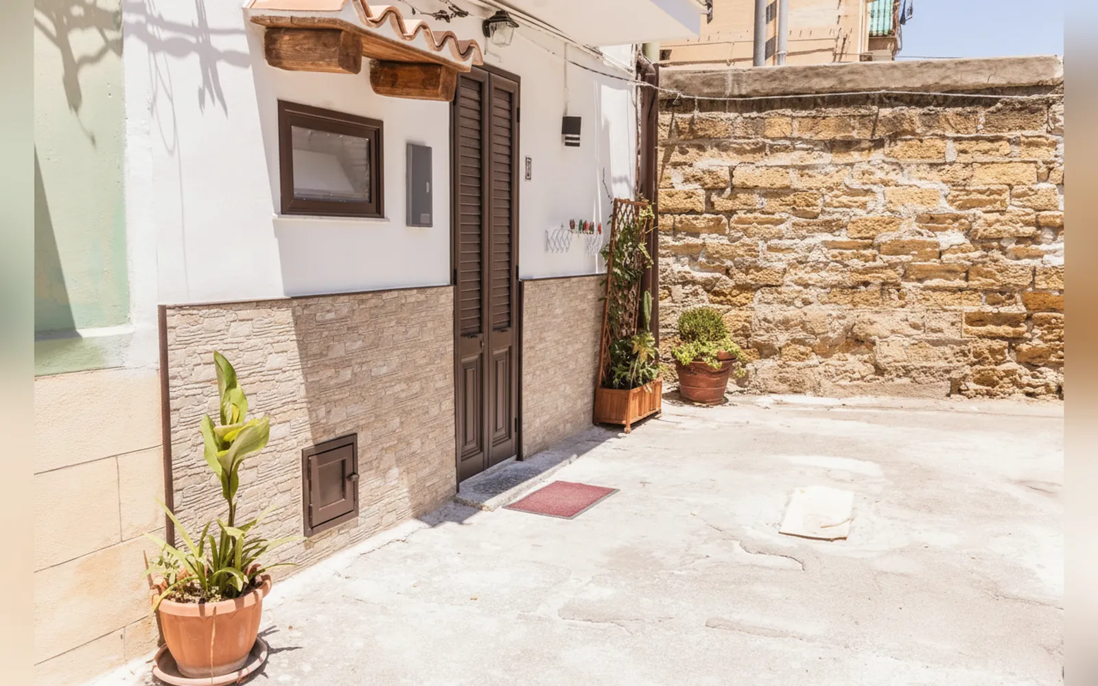 L’ingresso della casa al piano terra, con la porta in legno e le piante